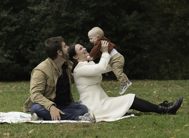 photo of parents and baby on the grass