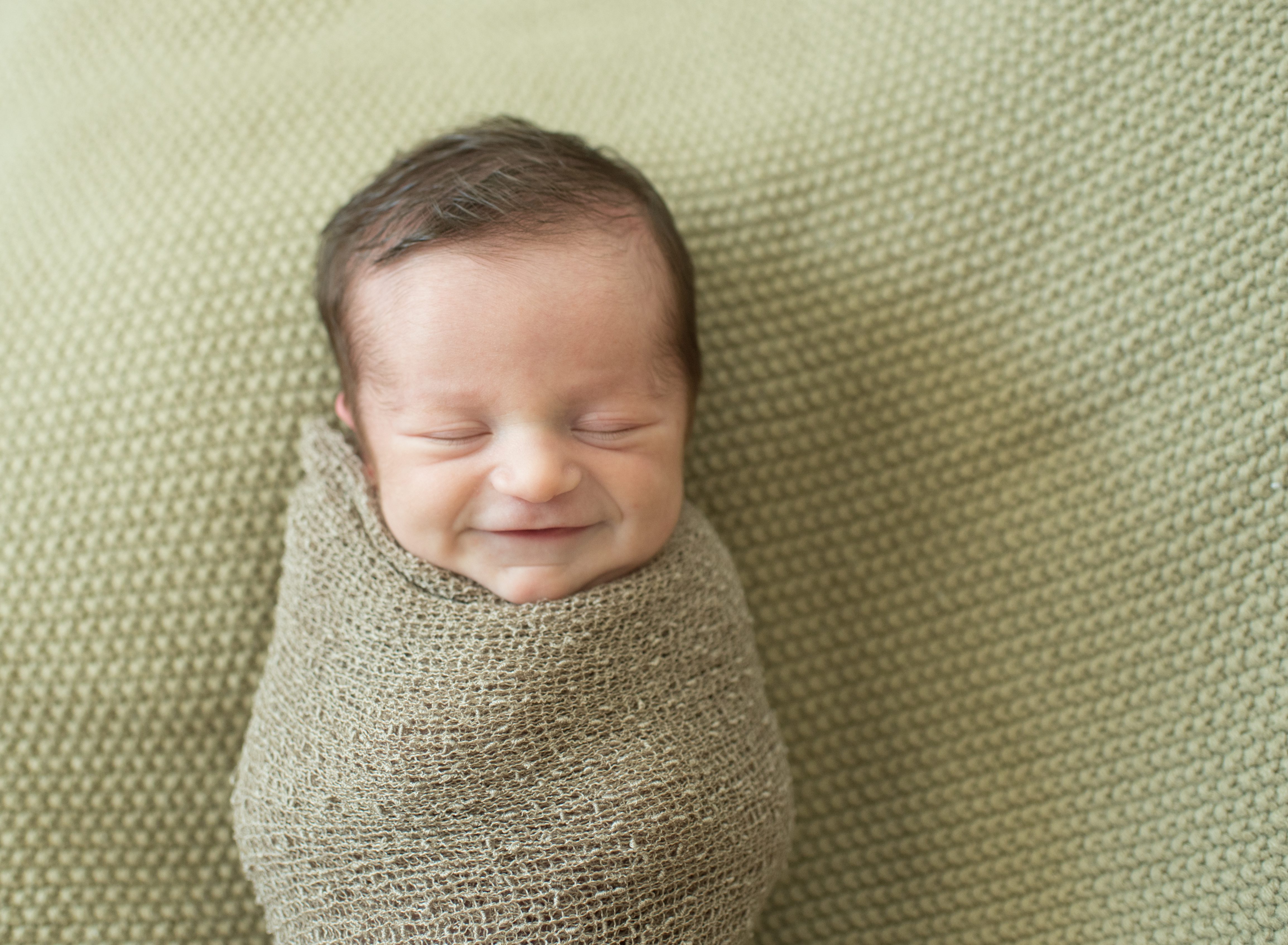 smiling newborn baby on blanket