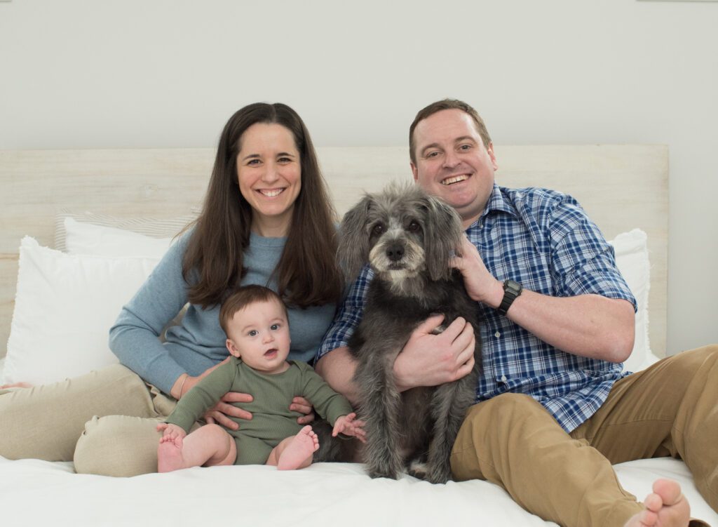 family photo of parents, baby and dog on their bed photo